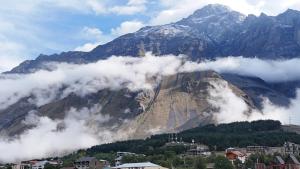 a mountain shrouded in clouds with a town and houses at ADRESATI Stepantsminda in Stepantsminda