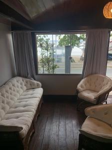 ein Wohnzimmer mit zwei Stühlen und einem Fenster in der Unterkunft Hotel Pé na Areia in Penha