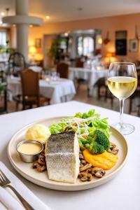 ein Teller mit Essen auf einem Tisch mit einem Glas Wein in der Unterkunft Hôtel de Bretagne Dol centre ville - Hotel et Restaurant in Dol-de-Bretagne