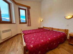 een slaapkamer met een bed met een rood dekbed bij Résidence Saboia B54 Clés Blanches Courchevel in La Tania