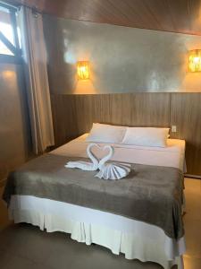 ein Bett mit zwei weißen Schwänen, die wie Herzen aussehen. in der Unterkunft Hotel Pé na Areia in Penha