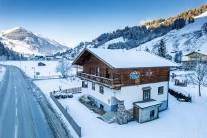a wooden house in the snow next to a road at Chalet Fabian by we rent, JOKERCARD INCLUDED in Saalbach-Hinterglemm