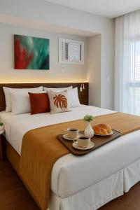 una camera da letto con un letto con due tazze e croissant di Flat Praia do Canto Collection View a Vitória Altre 70 foto