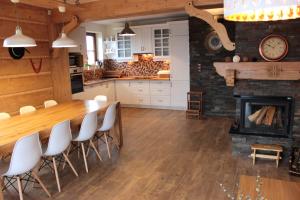 a kitchen with a bar with white chairs and a fireplace at Willa Misiowa Chata in Czarna Góra