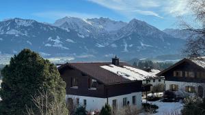 a house with snowy mountains in the background at Ferienwohnung Panoramablick in Bolsterlang