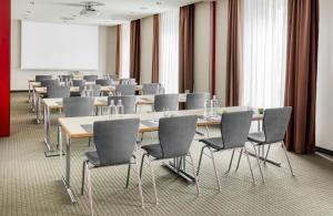 a conference room with tables and chairs and a screen at Hotel Nürnberg City Center by Leonardo Hotels in Nürnberg