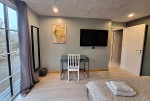 a bedroom with a table and a television on the wall at Odense Garden Apartment in Odense