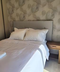 Una cama con sábanas blancas y almohadas en una habitación. en Moderno y equipado, cerca del Paseo la Galeria, en Asunción