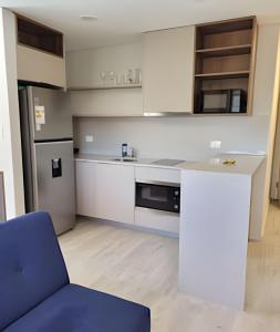 una cocina con armarios blancos y una silla azul en Moderno y equipado, cerca del Paseo la Galeria, en Asunción