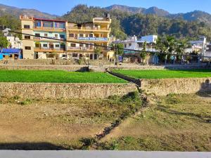 a large building in front of a field with houses at Gungun Homestay in Rishīkesh