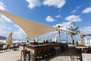 een bar op het strand met stoelen en parasols bij Dessole Malia Beach - All Inclusive in Malia