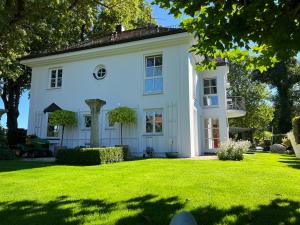 ein weißes Haus mit einem großen Hof in der Unterkunft Herrenhaus - Starnberger See - Ammerland in Münsing