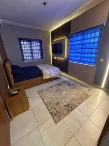 a bedroom with a bed and a rug and two windows at Max Court in Ikeja