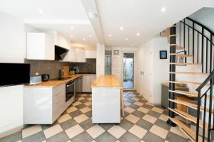 a kitchen with white cabinets and a spiral staircase at Charmante maison à 200m de la plage in Hossegor