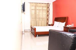 Un dormitorio con una cama y un sofá en una habitación. en Geed Hotel, en Nairobi 21 fotos más