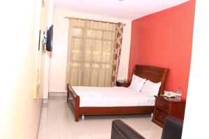 Un dormitorio con una cama y una pared roja. en Geed Hotel, en Nairobi