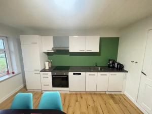 a kitchen with white cabinets and a green wall at Wohnung in Salling in Buksager