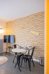 een tafel en stoelen in een kamer met een bakstenen muur bij Studio Beach House à Sangatte bord de plage in Sangatte