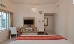 a bedroom with a bed and a desk and a television at Hotel Sumandeep 
