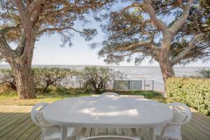 a white table and chairs on a deck with the beach at Villa Germaine les pieds dans l'eau in Andernos-les-Bains