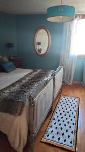 een slaapkamer met een bed met een spiegel en een tapijt bij Maison Jacquemin in Saint-Pierre