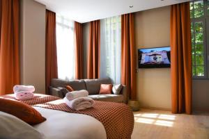 una camera da letto con un letto, un divano e una TV di LE CASTEL D'ALTI a Luchon