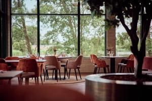 a restaurant with tables and chairs and a large window at Van der Valk Hotel Sneek in Sneek