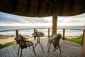 a porch with two chairs and a table on the beach at Monarch Beach Villa in Cimbene
