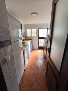 cocina con nevera y suelo de baldosa. en La Casita de Marisol, en El Real de la Jara