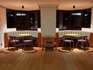 two tables and chairs in a room with windows at Tieflehner Hof Pitztalhaus Hotel in Sankt Leonhard im Pitztal