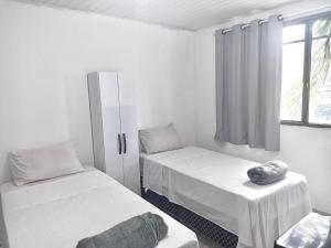 una stanza bianca con due letti e una finestra di Hotel Balneário ad Angra dos Reis