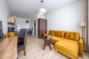 a living room with a yellow couch and a table at ApartamentyPrzyMorzu Diva 553 in Kołobrzeg