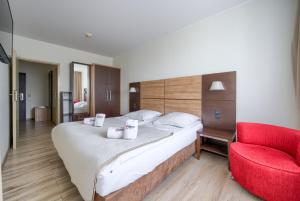 a bedroom with a large bed and a red chair at ApartamentyPrzyMorzu Diva 553 in Kołobrzeg