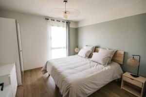 a bedroom with a bed with white sheets and a window at Villa Moka - private pool in Saumane-de-Vaucluse