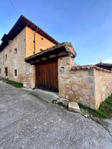 Un edificio de piedra con una puerta de madera en una calle. en CASA RURAL PALACIO LOS LABREQUINES, en Villacomparada de Rueda