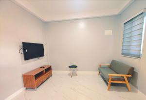 a living room with a couch and a tv on a wall at Casanuestra Apartelle in Panglao