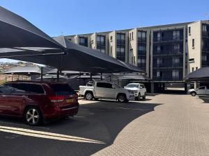 a parking lot with cars parked in front of a building at Wild Olive 65 Farmhouse Style in Windhoek