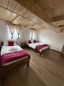 two beds in a large room with wooden ceilings at Apartmány u náměstí in Chřibská +19 photos