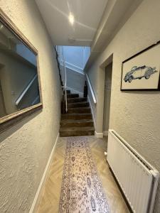 Un pasillo con escaleras y una imagen de un coche en la pared. en The Quirky Townhouse, Hawick, en Hawick