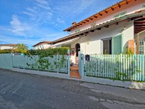 einen weißen Zaun vor einem Haus mit einem Tor in der Unterkunft I Cipressi in Cinquale