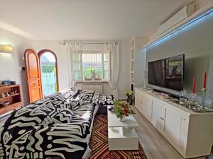 ein Wohnzimmer mit einem Bett mit Zebramuster und einem Fernseher in der Unterkunft I Cipressi in Cinquale