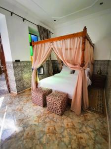 乌季达Riad Dar Al Fassia的带天蓬床和椅子的卧室