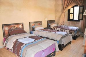 a group of four beds in a room at Auberge jawahir aguerd paradise valley in Aguerd +74 photos