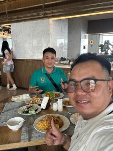 two men sitting at a table with plates of food at Apec mandala Apartment - APEC Mandala Ocean View Mũi né-R0234 in Mui Ne