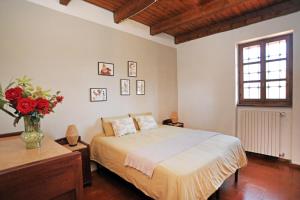 a bedroom with a bed and a vase with red flowers at Il portico sulla valle, Bioglio in Valle San Nicolao