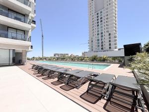 a row of lounge chairs next to a swimming pool at Dpto con piscina a pasos del Shopping del Sol in Asuncion