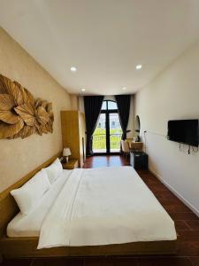 1 dormitorio con 1 cama blanca grande y TV en StayLa Homestay, en Phu Quoc