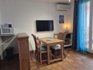 een eetkamer met een tafel en een televisie bij Tokelau - Vue Mer in Sausset-les-Pins