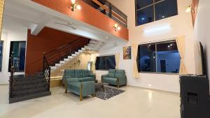 a living room with two chairs and a staircase at CocoAura - Tropical Luxury Villa with Pool&Jacuzzi in Utan