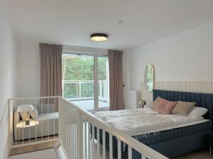 een slaapkamer met een bed en een balkon bij Nadmorska Florina Apartamenty dwupoziomowe z tarasami in Łeba